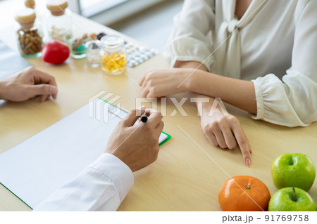 Woman meet with professional nutritionist in hospital and taking a supplement pills close up with copyspace. Nutritionist give a recommendation to young woman patient. Woman meet with professional nutritionist in hospital and taking a supplement pills close up with copyspace. Nutritionist give a recommendation to young woman patient. 91769758