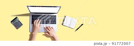 Person using a laptop computer with a notebook Person using a laptop computer with a notebook 91772007