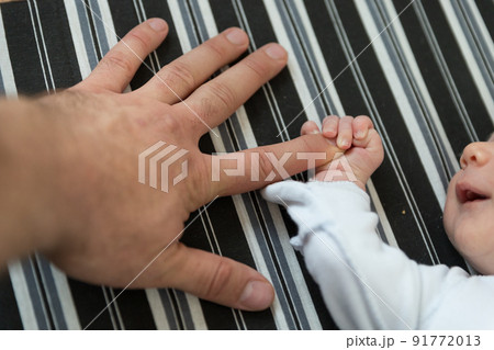 A newborn baby holding the finger of his father A newborn baby holding the finger of his father 91772013