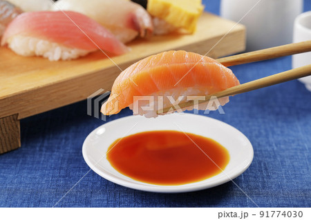 箸で持ち上げたサーモンの握り寿司 91774030