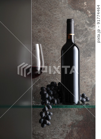 Bottle and a glass of red wine with a bunch of blue grapes. Bottle and a glass of red wine with a bunch of blue grapes. 91774464
