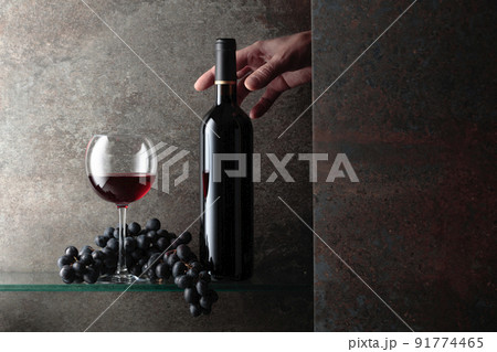Hand reaches for a bottle of red wine. Hand reaches for a bottle of red wine. 91774465