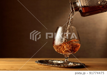 Brandy is poured into a snifter glass. 91774475