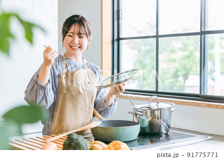 キッチンで料理の味見をする女性 91775771