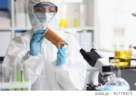 Woman in protective respirator and white coverall researching filter in lab Woman in protective respirator and white coverall researching filter in lab 91776875