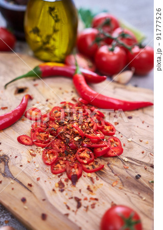 Fresh red chili peppers round slices on wooden cutting board at domestic kitchen 91777526