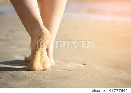 Girl's bare feet on the sea sand close up 91777642