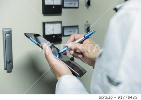 工場でタブレットを操作する作業員男性手元 91778435