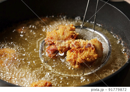 油で揚げている美味しそうな鶏の唐揚げ 91779872