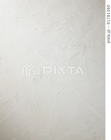 コテ跡の残る漆喰塗りの壁に光があたる縦長の背景画像 91781360