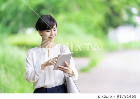 屋外でタブレットを操作するビジネスウーマン　タブレットを使う若い女性 91781469