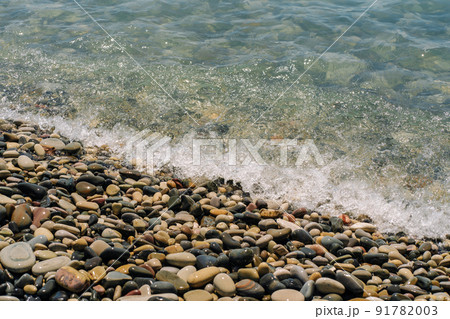 Bank of pebbles with the sea and beach in the background. 91782003
