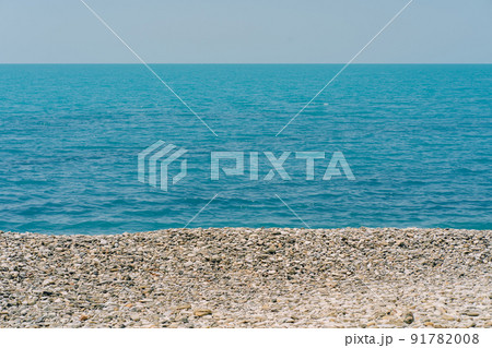 Bank of pebbles with the sea and beach in the background. Bank of pebbles with the sea and beach in the background. 91782008