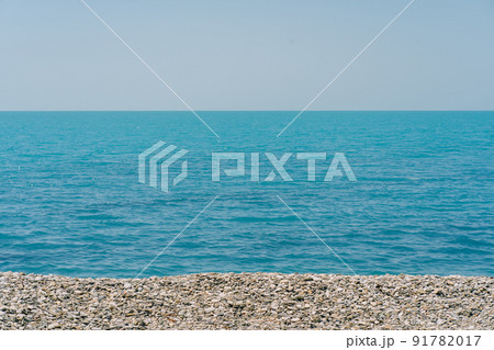 Bank of pebbles with the sea and beach in the background. 91782017