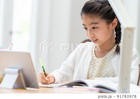 タブレットを見ながら勉強する小学生の女の子 91783978
