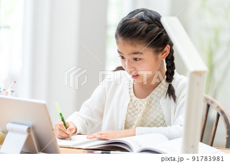 タブレットを見ながら勉強する小学生の女の子 91783981
