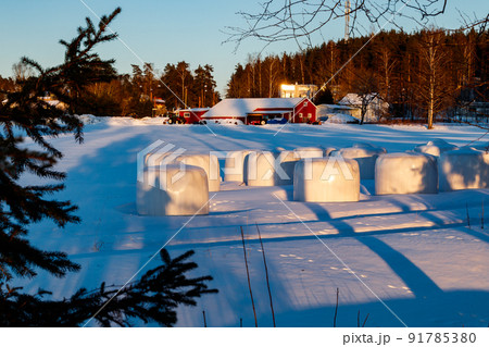 A winter country landscape with hay bales and hare tracks on snowy field in sunset. A winter country landscape with hay bales and hare tracks on snowy field in sunset. 91785380