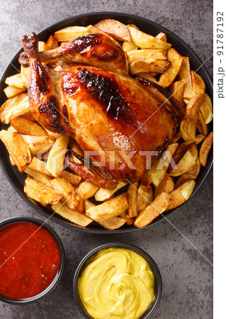 Pollo a la Brasa Peruvian Roast Chicken with fried potato and sauces closeup in the plate. Vertical top view 91787192