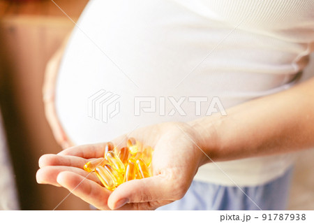 Healthcare, treatment, supplements. Happy smiling woman taking pill with supplement vitamin Omega 3. Pregnancy, medicine health care concept. 91787938