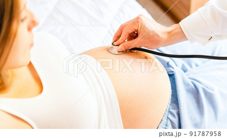 Pregnant woman doctor hospital. Medical clinic for pregnancy consultant. Doctor examining pregnancy woman belly holding stethoscope. Therapy, healthcare, motherhood concept. Pregnant woman doctor hospital. Medical clinic for pregnancy consultant. Doctor examining pregnancy woman belly holding stethoscope. Therapy, healthcare, motherhood concept. 91787958