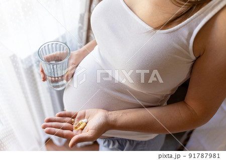 Pregnant woman pills vitamin. Happy smiling woman taking pill with supplement vitamin Omega 3. Vitamin D, E, A Fish Oil Capsules. Pregnant woman pills vitamin. Happy smiling woman taking pill with supplement vitamin Omega 3. Vitamin D, E, A Fish Oil Capsules. 91787981