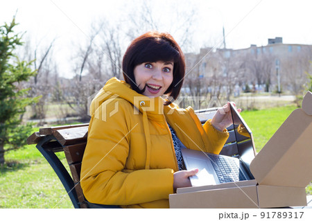 A girl opens a box with a laptop, a gift from her beloved husband 91789317