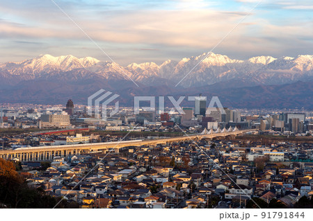 呉羽山展望台から望む立山連峰と北陸新幹線の高架橋が走る富山市の中心部 91791844