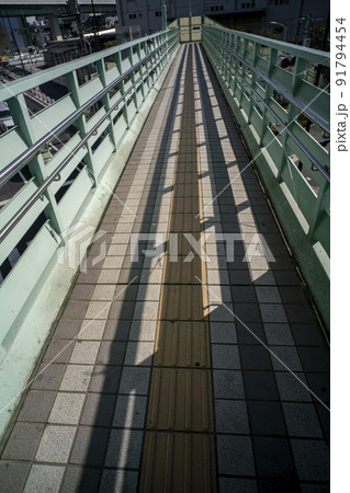 首都高の下をはしる点字ブロックのある手摺の影が映る長い歩道橋・北区堀船 首都高の下をはしる点字ブロックのある手摺の影が映る長い歩道橋・北区堀船 91794454