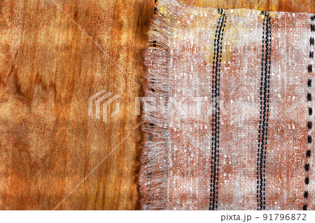 A white kitchen towel lies on the countertop of a wooden table. The fringed towel is fringed and patterned on the rough boards. Digital watercolor painting 91796872