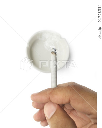 A man's hand flicks the ashes of the burning cigarette in the ashtray. Smoking is harmful to health A man's hand flicks the ashes of the burning cigarette in the ashtray. Smoking is harmful to health 91798554