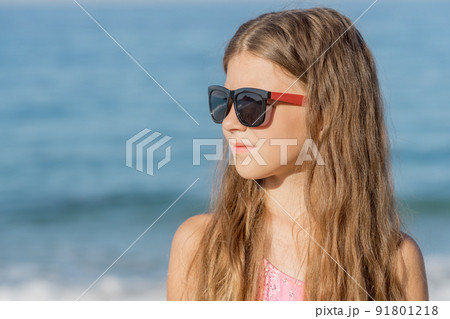 Close-up portrait of a girl in a bathing suit and glasses. 91801218