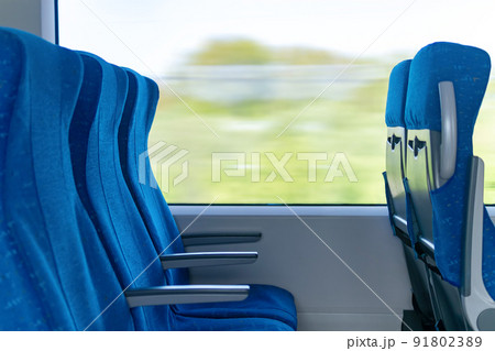interior of commuter passenger train car, row of chairs and a motion-blurred landscape outside the window interior of commuter passenger train car, row of chairs and a motion-blurred landscape outside the window 91802389