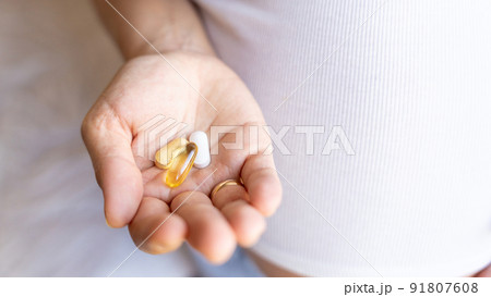 Pregnant woman pills vitamin. Happy smiling woman taking pill with supplement vitamin Omega 3. Vitamin D, E, A Fish Oil Capsules. 91807608