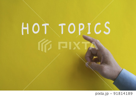 Hand pointing Hot Topics text on yellow cover background. 91814189