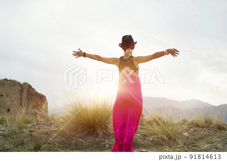 rear view of a young asian woman in red dress embracing the morning sunlight in a deserted mountain area 91814613