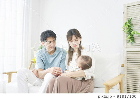 リビングで昼寝する赤ちゃんを見る両親 リビングで昼寝する赤ちゃんを見る両親 91817100