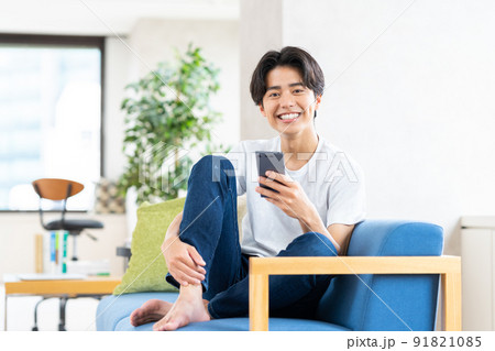 リビングでスマホを見る若い男性 リビングでスマホを見る若い男性 91821085