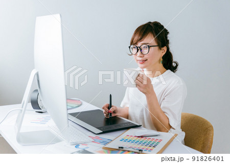 ペンタブで絵を描く制作会社の日本人女性（飲み物） 91826401