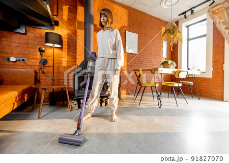 Woman cleaning floor with handheld vacuum cleaner 91827070