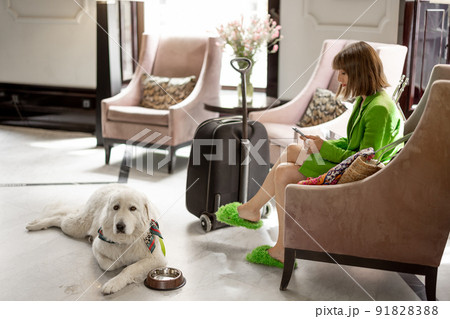 Business woman with dog in lobby of hotel Business woman with dog in lobby of hotel 91828388