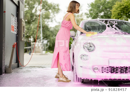 Woman washing her car at self-service car wash 91828457