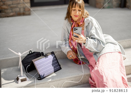 Woman charge phone from a portable solar panel 91828613