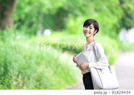屋外でタブレットを持つビジネスウーマン　タブレットを使う若い女性 91829434