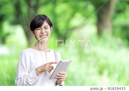 屋外でタブレットを操作するビジネスウーマン　タブレットを使う若い女性 91829435