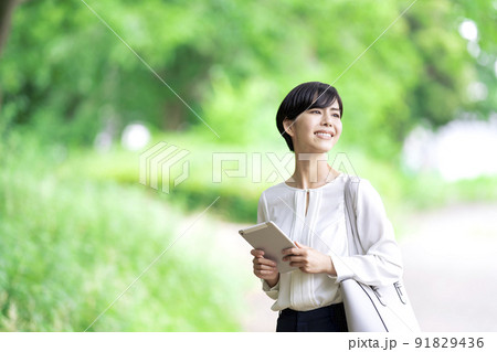 屋外でタブレットを操作するビジネスウーマン　タブレットを使う若い女性 91829436