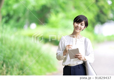 屋外でタブレットを操作するビジネスウーマン　タブレットを使う若い女性 91829437