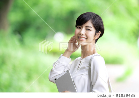 屋外でタブレットを持つビジネスウーマン　タブレットを持つ若い女性 91829438