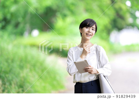 屋外でタブレットを操作するビジネスウーマン　タブレットを使う若い女性 91829439