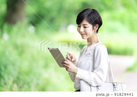 屋外でタブレットを操作するビジネスウーマン　タブレットを使う若い女性 91829441
