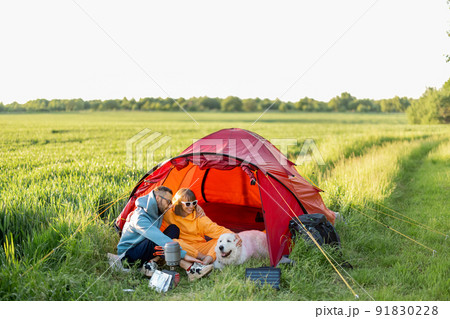 Couple and pet at campsite with tent on a green field Couple and pet at campsite with tent on a green field 91830228